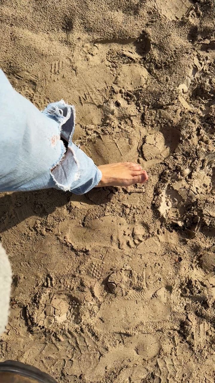 Nackter Fuß im Sand von Byron Bay direkt neben den gerade ausgezogenen Lederboots