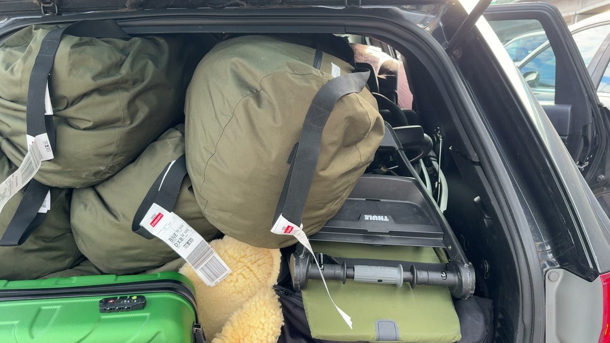Vollgepackter Kofferraum des Jeeps: olivgrüne Seesäcke mit Emirates-Anhängern, ein grüner Handgepäck-Koffer und ein zusammengeklappter Buggy